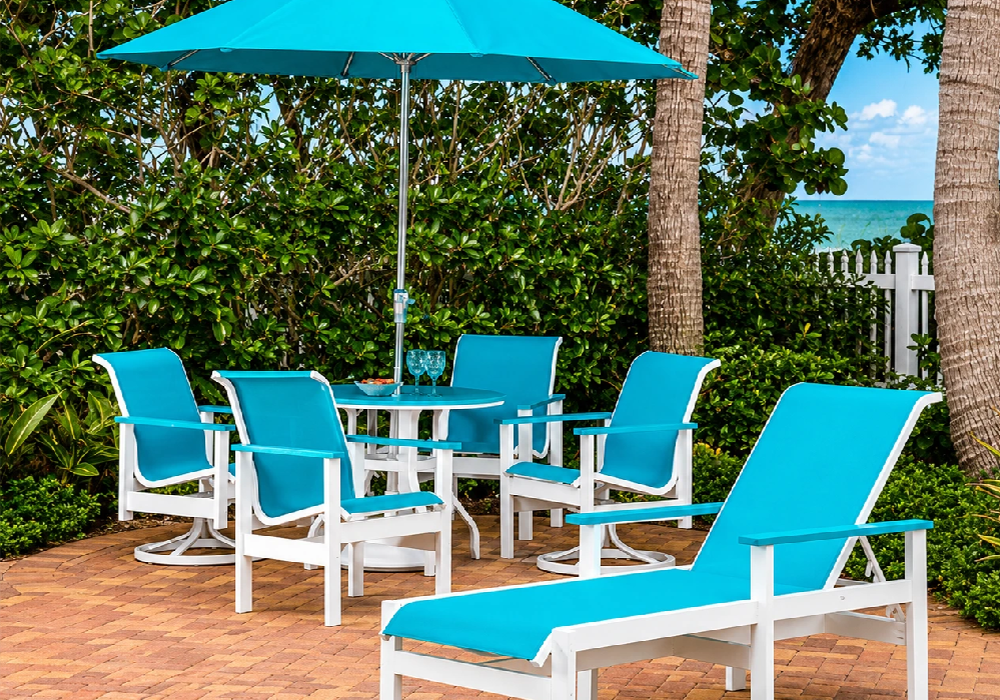 Resort pool deck featuring turquoise Marine Grade Polymer outdoor dining chairs and chaise lounges under a matching umbrella for a vibrant tropical atmosphere.